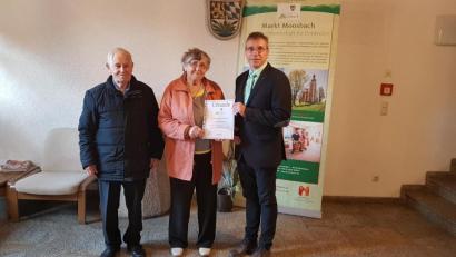 Bild: gi
Das Ehepaar Hildegund und Helmut Neumaier aus Lindau verbringt seinen 40. Aufenthalt in Moosbach. Als Dank für die Treue überreichte ihnen Bürgermeister Hermann Ach einen Gutschein mit Urkunde.