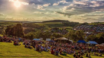 Archivbild: Hermann Koch 
So sah es im Juli 2016 auf der Schmie-Alm aus: Das Publikum schaut beim Sonnenuntregang auf die Bühne und die Dächer Freudenbergs.