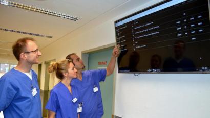 Bild: exb/Marion Hausmann
Das „Arrival Board“ in der Zentralen Notaufnahme verrät den beiden Oberärzten Dr. Thomas Scherl (linke) und Dr. Florin Bodea sowie der Fachkrankenschwester Johanna Rieppel, wann Patienten mit welcher Verdachtsdiagnose von den Rettungsdiensten ins Krankenhaus St. Barbara gebracht werden.
