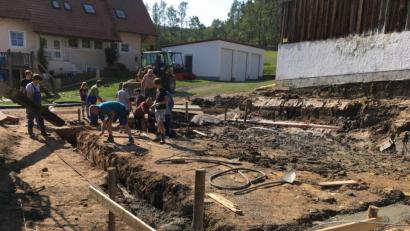 Bild: u
Nachdem Christian Riß das Grundstück im Ortskern zur Verfügung gestellt und Bauunternehmer Sepp Falk die Planung für das Gemeinschaftshaus entworfen hatte, wurde im September 2018 die Baumaßnahmen mit dem Erdaushub, dem Einbringen einer Bodenplatte und dem Errichten einer Stützmauer begonnen. Dabei packten Jung wie Alt an.