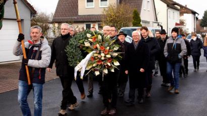 Bild: R. Kreuzer
Mit einem Schweigemarsch durch den Ortsteil errichten die Menschen den Gedenkstein, die Fahne der Siedlergemeinschaft geht voran.