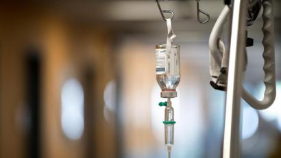 Archivbild: Fabian Sommer/dpa
Ein Tropf hängt an einem Krankenhausbett auf dem Flur der Notaufnahme eines Klinikums.