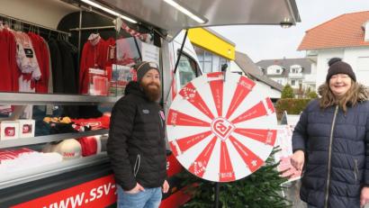 Bild: Hirsch
Fanshop-Begleiter Simon Raab (links) ließ Jahn-Fan Tanja Dineiger (rechts) am Glücksrad drehen. Sie gewann eine rote Christbaumkugel mit Jahn-Emblem und kaufte noch weitere dazu. Das Jahn-Mobil machte am Samstag auf dem Netto-Parkplatz Halt.