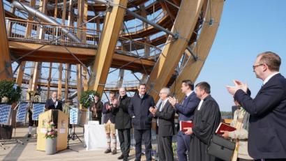 Archivbild: Christopher Dotzler
Zur Eröffnung der Erlebnisholzkugel am 1. April heißt InMotion-Park-Geschäftsführer Tom Zeller (am Rednerpult) zahlreiche Gäste willkommen. Begeistert von der neuen Attraktion zeigen sich dabei auch Ministerpräsident Markus Söder (Sechste von rechts) und Minister Albert Füracker (links daneben).