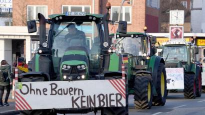 Bild: Carsten Rehder
Schlagendes Argument: Landwirte nach einer Sternfahrt in Kiel. An einem Trecker warnt ein Schild mit der Aufschrift „Ohne Bauern KEIN BIER“. Foto: Carsten Rehder/dpa