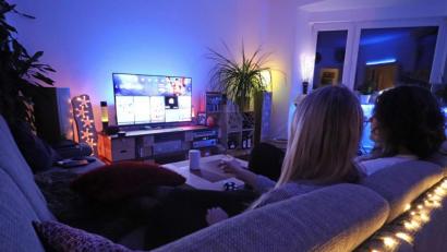 Bild: Nina Drewes/dpa
Alexa, mach das Licht blau!“ Zwei Frauen im Wohnzimmer mit Smart TV und LED-Beleuchtung, deren Helligkeit und Farbton sich per Sprachsteuerung anpassen lassen.
(Gestellte Szene)