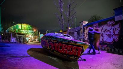 Bild: Lino Mirgeler/dpa
Personen gehen an einem ausrangierten Boot vor dem Eingang des Nachtclubs "Bahnwärter Thiel" vorbei.