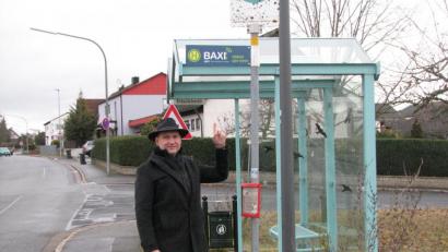 Bild: knh
Bürgermeister Richard Kammerer zeigt auf eines der BAXI-Schilder an der Haltestelle „Kreuzäckersiedlung“. BAXI-Haltestellen sind an den bekannten Bushaltestellen sowie im Ebenweg gegenüber dem Kindergarten und in Steinfels.