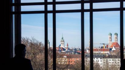 Bild: Lino Mirgeler
Ein Abgeordneter blickt aus einem Fenster des Landtags auf die Skyline von München mit der Frauenkirche.