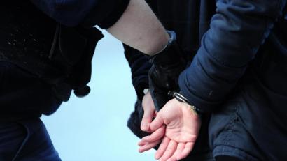 Grafik: Daniel Reinhardt/dpa
Polizisten führen einen in Handschellen gefesselten Mann ab.