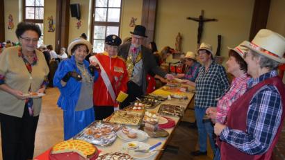 Bild: jr
Sturm ans reichhaltige Buffet: 26 selbst gebackene Kuchen und Torten standen zur Auswahl. Anstellen mussten sich selbst Queen Elizabeth II. (Marianne Bauernfeind) und Prinz Philip (Herma Laumer) sowie Stadtpfarrer Anton Witt (hinten).