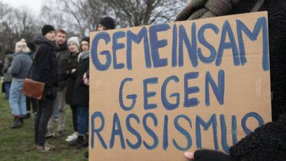 Bild: Paul Zinken/dpa
Eine Teilnehmerin der Gedenkfeier für die Terroropfer des Anschlages im neuseeländischen Christchurch mit einem Pappschild mit der Aufschrift "Gemeinsam gegen Rassismus".