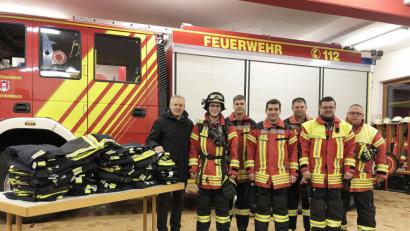 Bild: jma
Bürgermeister Jürgen Kürzinger (links) übergibt im Gerätehaus die neuen Schutzhosen für die Feuerwehr.
