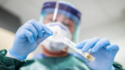 Bild: Marcel Kusch/dpa
Die Stationsleiterin auf der Infektionsstation eines Krankenhauses steht in Schutzkleidung und mit einer Atemmaske in einer Schleuse und hält ein Abstrichröhrchen in den Händen.