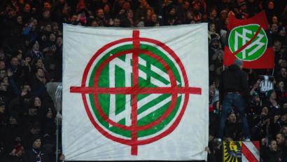 Bild: Nicolas Armer/dpa
Nürnberger Fans halten am Freitagabend ein Banner mit dem Logo des DFB in die Höhe, das in einem Fadenkreuz zu sehen ist.