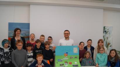 Bild: du
Die 16 Kinder der vierten Grundschulklasse mit Fachlehrerin Anna Reissinger (hinten, links) haben an Bürgermeister Ernst Lenk (Mitte) viele Fragen. Am Schluss überreichen sie ihm eine Bildtafel über Schirmitz.