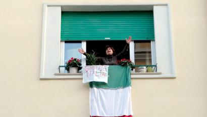 Bild: Mauro Scrobogna/LaPresse via ZUMA Press/dpa
Eine Bewohnerin Roms klatscht und singt am Fenster ihrer Wohnung. An ihrem Fenster hängt eine Landesfahne mit der Aufschrift "Grazie Italia".