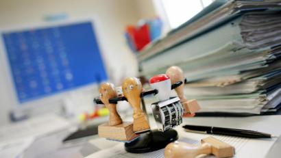 Bild: Patrick Pleul
ARCHIV - 06.09.2007, Frankfurt (Oder): ILLUSTRATION - Ein Stempelkarussell (Stempelhalter) steht neben einem Stapel Akten auf einem Schreibtisch in einer Behörde. 520 000 Stunden Zeitersparnis allein bei der Gewerbeanmeldung - die NRW-Regierung ist stolz auf ihre Erfolge beim Entrümpeln unnötiger Vorschriften. Hinter die meisten Versprechen im Bürokratie-Kapitel ihres Koalitionsvertrags kann sie bereits einen Haken setzen. Foto: Patrick Pleul/zb/dpa +++ dpa-Bildfunk +++