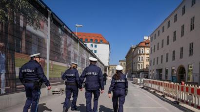 Archivbild: Peter Kneffel/dpa
Vier Polizisten patroullieren durch eine fast leere Straße.