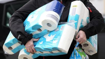 Bild: Rene Traut/dpa
Ein Mann trägt eingekauftes Toilettenpapier und Küchenrollen aus einem Supermarkt.
