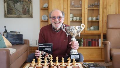 Bild: Wolfgang Steinbacher
Heinz Däubler hält zwei Dinge in Händen, übe die er sich sehr freut: den fünften Band seiner "Kniffeligen Schachaufgaben" und den Pokal für den Sieg im Seniorenturnier des Schachfestivals Bad Wörishofen.