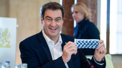 Bild: Sven Hoppe/dpa
Ministerpräsident Markus Söder (CSU) ist trotz Coronakrise das Lachen nicht vergangen: Bei einer Sitzung des bayerischen Kabinetts hält er einen Mundschutz mit der bayerische Rautenflagge in die Kameras. Eine Maskenpflicht wurde dort aber nicht beschlossen.