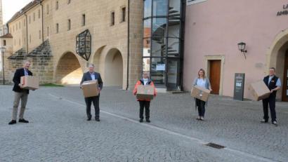 Bild: Christine Hollederer/exb
In jedem dieser Pakete befinden sich wertvolle FFP2- und Mund-Nasen-Schutzmasken, die an Senioren- und Pflegeheime im Landkreis verteilt werden. Von links: Werner Conrad, Landrat Richard Reisinger, Versorgungsarzt Dr. Michael Scherer sowie die Fachberater von BRK und ASB, Joanna Sladki und Andreas Brunner.