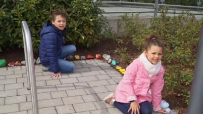 Bild: du
Die vierjährige Mia (vorne) und der siebenjährige Elias (hinten) tragen ebenfalls mit bunten Steinen zum Wachsen der "Schlange" rund um das Rathaus bei.