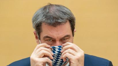 Bild: Peter Kneffel/dpa
Markus Söder (CSU), Ministerpräsident von Bayern, zieht sich für die Fotografen vor Beginn der Sitzung des bayerischen Landtags eine Mundschutzmaske auf.