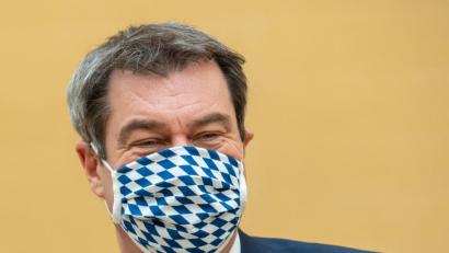 Bild: Peter Kneffel/dpa
München: Markus Söder (CSU), Ministerpräsident von Bayern, zieht sich für die Fotografen vor Beginn der Sitzung des bayerischen Landtags eine Mundschutzmaske auf.