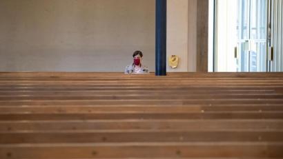 Bild: Sven Hoppe/dpa
Eine Frau mit Mundschutz verfolgt einen Gottesdienst in der ansonsten fast menschenleeren St. Matthäuskirche in München.