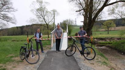 Bild: den
Der Windischeschenbacher Bürgermeister Karlheinz Budnik (links) kam mit einem E-Bike, das bei der Stadt auch ausgeliehen werden kann. Der scheidende Krummennaaber Rathauschef Uli Roth (rechts) trat traditionell in die Pedale. Karsten Heßing, Mitarbeiter im Amt für Ländliche Entwicklung in Tirschenreuth und Vorstand der Teilnehmergemeinschaft Steinwald, durchschnitt das Band für die neue Radbrücke in Trautenberg (im Hintergrund der Turm der KTB).