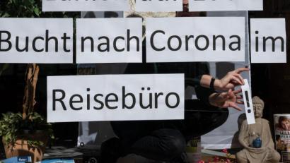 Bild: Bernd Thissen/dpa
Ein Mitarbeiterin klebt Blätter mit der Aufschrift „Bucht nach Corona im Reisebüro“ in das Schaufenster.