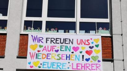 Bild: weu
Ein farbenfrohes Tuch, gefertigt von Sabine Lehner, mit der Aufschrift „Wir freuen uns auf ein Wiedersehen! Eure Lehrer“ hängt an der Außenwand der Grundschule und begrüßt die Schüler.