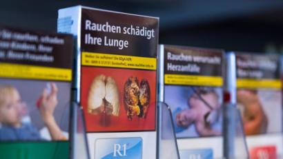 Archivbild: Monika Skolimowska/dpa
Zigarettenschachteln mit Schockbildern stehen in einem Regal.