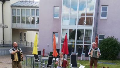 Bild: u
Zünftig bayerisch und beschwingt spielt auf Initiative von Hanna Ries (Mitte) das Trachtler-Musikantentrio im Innenhof des BRK-Seniorenwohn- und Pflegeheims auf und bereitet damit den Senioren eine freudige Überraschung und willkommene Abwechslung vom Corona-Alltag. Mit im Bild: Uwe Herrmann (links) und Franz Dolles (rechts).
