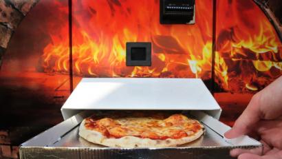 Bild: Karl-Josef Hildenbrand
Ein Kunde greift nach einer Pizza Margherita die nach etwa drei Minuten Backzeit aus einem Automaten ausgeworfen wird. Foto: Karl-Josef Hildenbrand/dpa