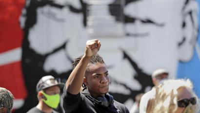 Bild: Elaine Thompson/dpa
Hanz Jouissance streckt zum Abschluss einer Mahnwache seine Faust in die Höhe. Landesweite Proteste richten sich nach dem gewaltsamen Tod des Afroamerikaners Floyd durch einen weißen Polizisten gegen Rassismus und Polizeigewalt. Die teils schweren Ausschreitungen in verschiedenen US-Metropolen dauern seit mehreren Tagen an.