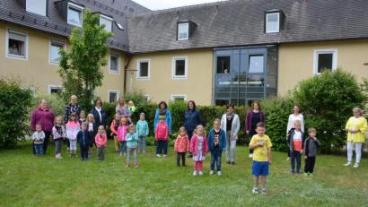 Bild: jr
Die 19 Kinder der aktuellen Notgruppe des Kinderhauses überraschten die Bewohnern des Seniorenzentrums Theresianum im garten mit einigen Liedern. Mit dabei (hintere Reihe, von rechts) waren Pflegedienstleiterin Henrike Neumann, Direktorin Lisa Zang und Kinderhausleiterin Imke Steinert.