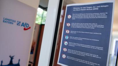 Bild: Sven Hoppe/dpa 
Eine Infotafel für das Tragen, An- und Ablegen von Mund-Nasen-Schutz hängt an einer Tür des bayerischen Landtags.