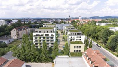 Bildmontage: exb/Immo VBOM
In unmittelbarer Nähe zur Max-Reger-Halle (rechts) und direkt am Stadtzentrum Weidens wird das Quartier "Neue Naabwiesen“ das künftige Stadtbild prägen. In fünf Gebäuden entstehen bis 2022 mehr als 100 Wohnungen und Geschäftsräume.