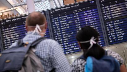 Bild: Matthias Balk/dpa
Reisende mit Mundschutz schauen auf eine Anzeigetafel am Münchner Flughafen, auf der zahlreiche internationale Flugziele gelistet sind.