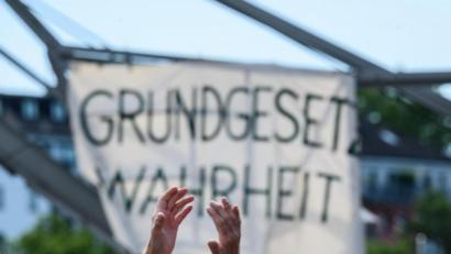 Bild: Andreas Arnold/dpa
Ein Demonstrant klatscht vor einem Plakat mit dem Slogan «Grundgesetz Wahrheit».