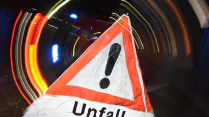 Symbolbild: Patrick Seeger/dpa
Ein Warndreieck mit dem Schriftzug „Unfall“ steht vor einem Blaulicht auf der Straße.