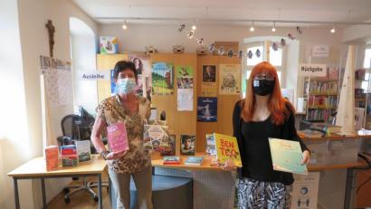 Bild: jzk
Christine Schubert (links) und Deborah Bregler präsentieren einige der neu angeschafften Bücher. Die Plätze für „Ausleihe“ und „Rückgabe“ sind getrennt. Plexiglasscheiben schützen als Spritzschutz vor der Ansteckung.