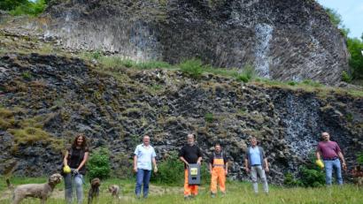Bild: bey
Nicole Holtmeier (links) und Wolfgang Schreffl (rechts) haben die leuchtend gelbe Tüte für das Einsammeln des Hundekots schon mal in die Hand genommen. Bauhofleiter Erwin Glaubitz hat den Spender in der Hand, der dort an der vor der Basaltwand vor der öffentlichen Toilette angebracht wird. Bürgermeister Reinhard Sollfrank (Zweiter von rechts) ist zuversichtlich, dass das Angebot des Marktes ein Beitrag zum Schutz der Umwelt beträgt.