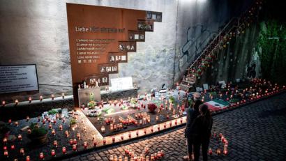 Bild: Fabian Strauch/dpa
Menschen stehen vor Kerzen an der Gedenkstätte. Vor dem 10. Jahrestag der Massenpanik bei der Loveparade, bei der 21 Menschen sterben, findet die «Nacht der 1000 Lichter» statt. Im stillen Gedenken an die Opfer des Loveparade-Unglücks zünden Menschen Kerzen an der Gedenkstätte und dem Tunnel an der Karl-Lehr-Straße am Vorabend des Jahrestages an.