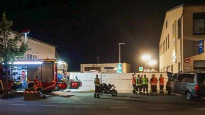 Bild: Markus Zechbauer/dpa
Feuerwehrleute stehen in der Nähe des Tatorts vor der Zufahrt zu einem Supermarkt.