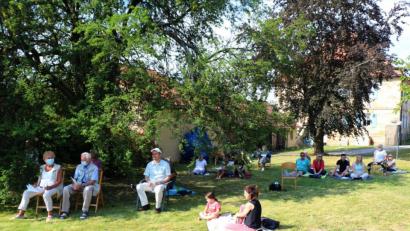 Bild: rpp
Die Gottesdienstbesucher verteilen sich für den Picknick-Gottesdienst im Pfarrgarten. Wegen der kräftigen Sonne sind die Schattenplätze schnell belegt.