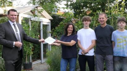 Bild: Wolfgang Grosser/exb
Landrat Thomas Ebeling (links) überreicht der Familie Andrea und Josef Fischer aus Schwarzenfeld die Auszeichnung „Bayern blüht – Naturgarten“.